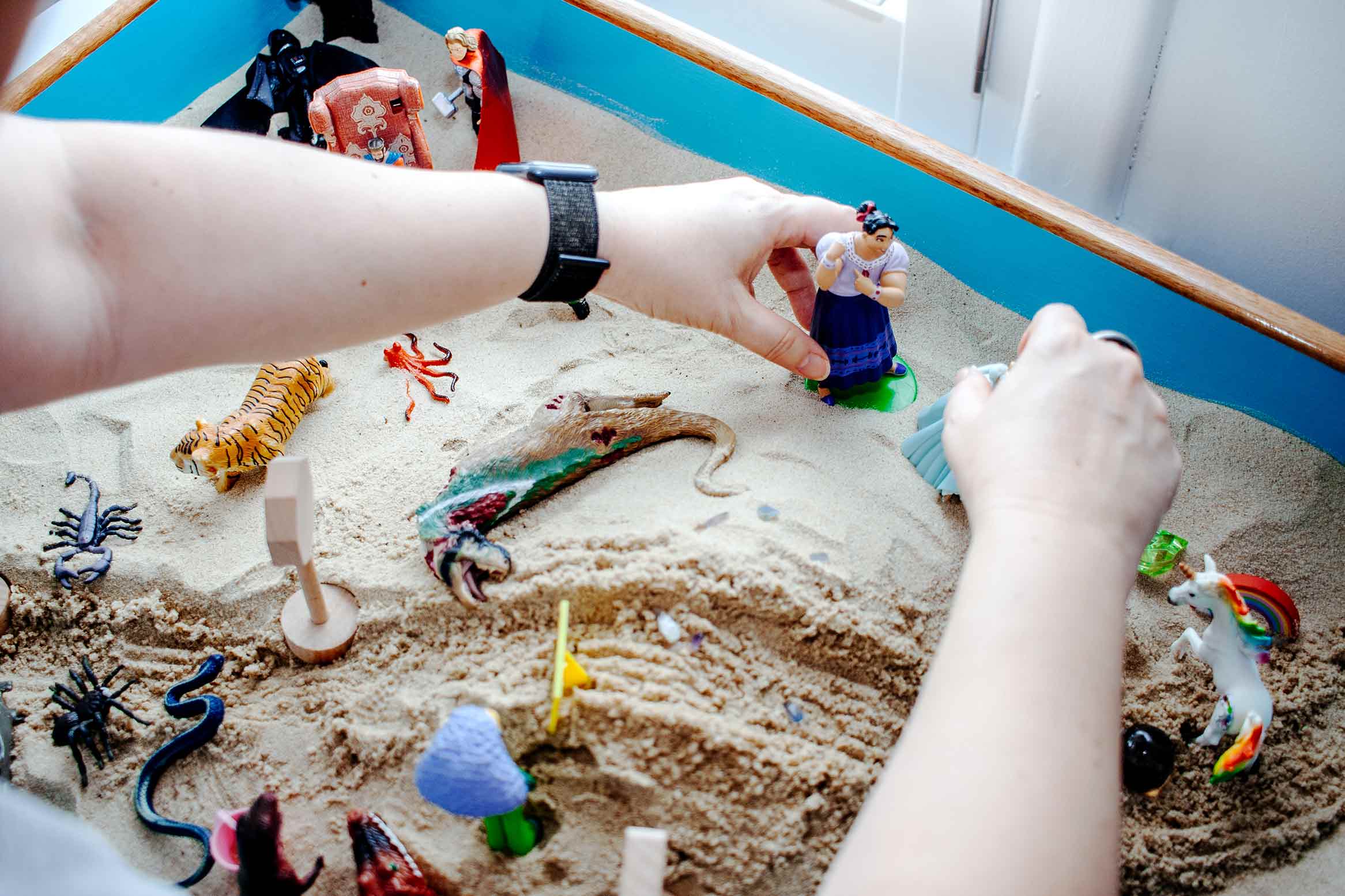 Hands in sand pit playing with toys